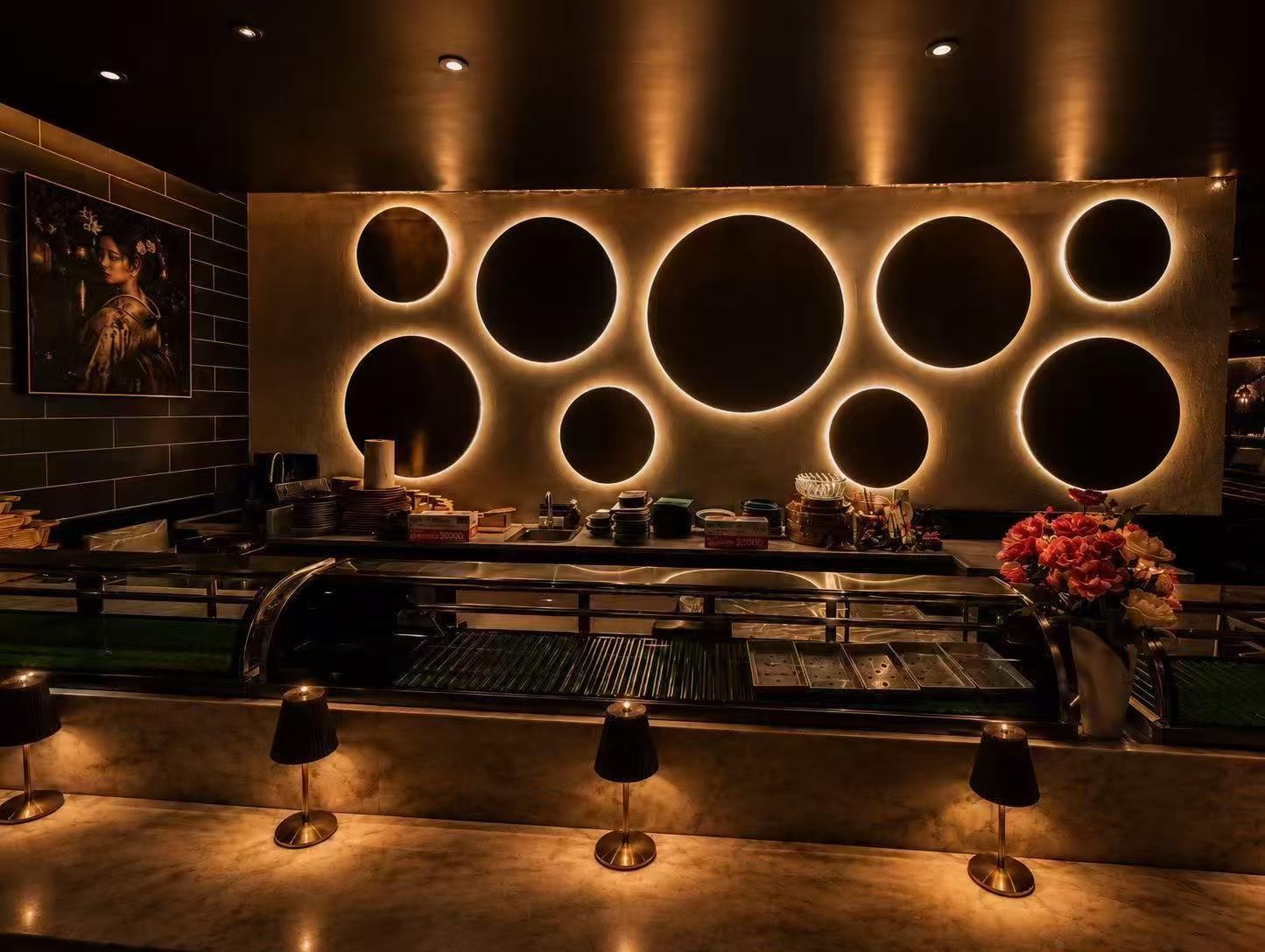 Dimly lit marble sushi bar with backlit circular wall cutouts and small table lamps at Origami Asian Fusion Exton, an Asian Fusion Restaurant in Exton