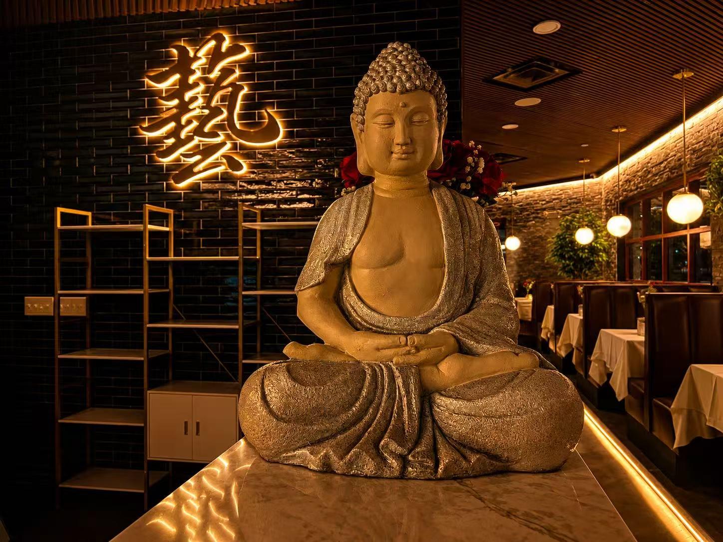 Large stone Buddha statue beside glowing Chinese character neon wall sign at Origami Asian Fusion Exton, an Asian Fusion Restaurant in Exton