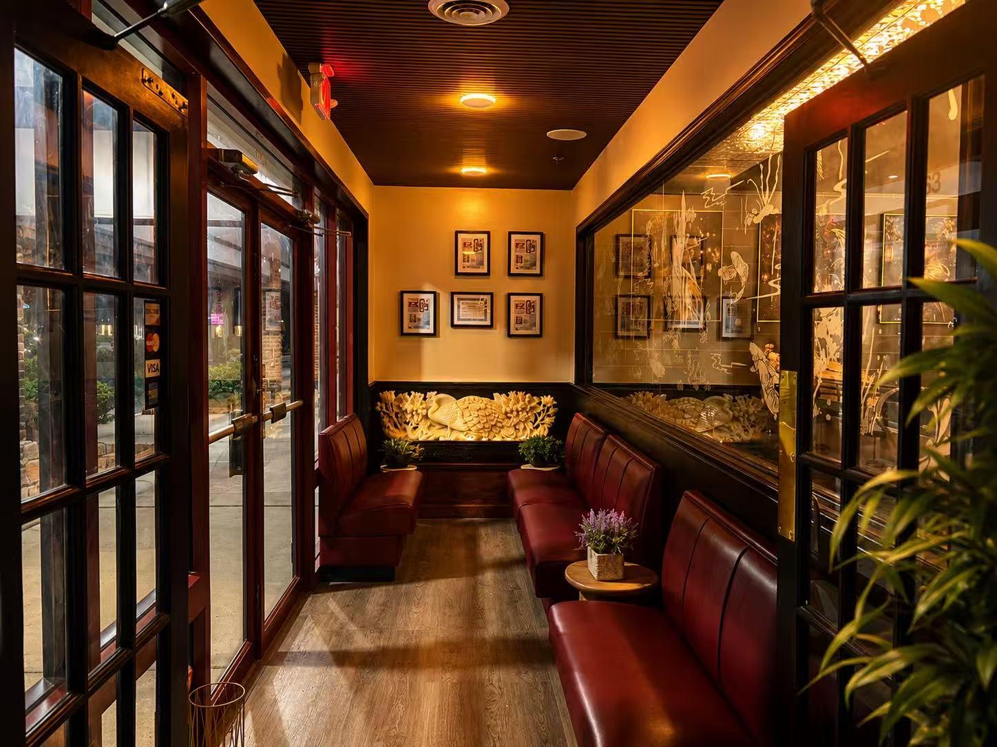 Front entrance lobby with red leather bench seating and framed wall art at Origami Asian Fusion Exton, an Asian Fusion Restaurant in Exton