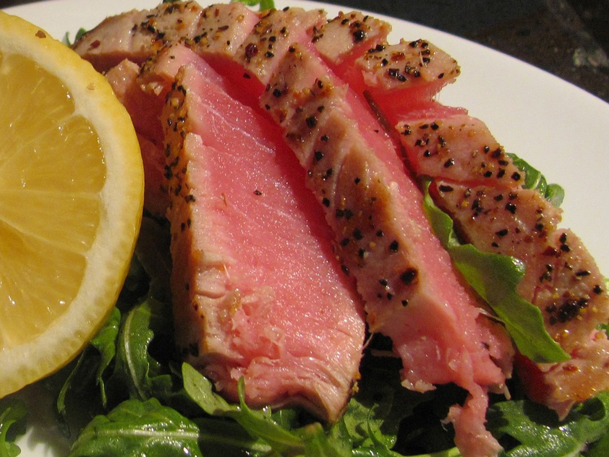 Seared tuna steak slices on a bed of arugula with lemon wedge at Oroshi Sushi Omakase, a Japanese Restaurant in Philadelphia