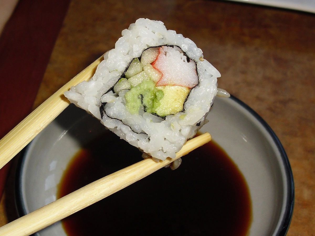 California sushi roll held by chopsticks above soy sauce at Oroshi Sushi Omakase, a Japanese Restaurant in Philadelphia