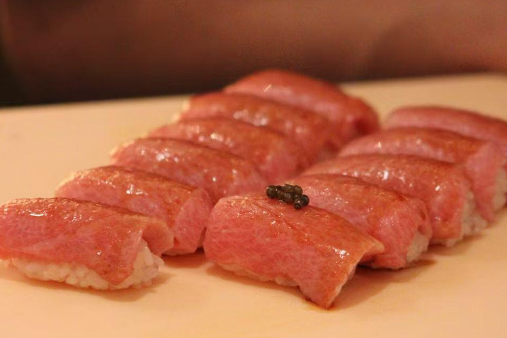 Glossy toro nigiri sushi, one topped with caviar, arranged on a light wooden board at Oroshi Sushi Omakase, a Japanese restaurant in Philadelphia