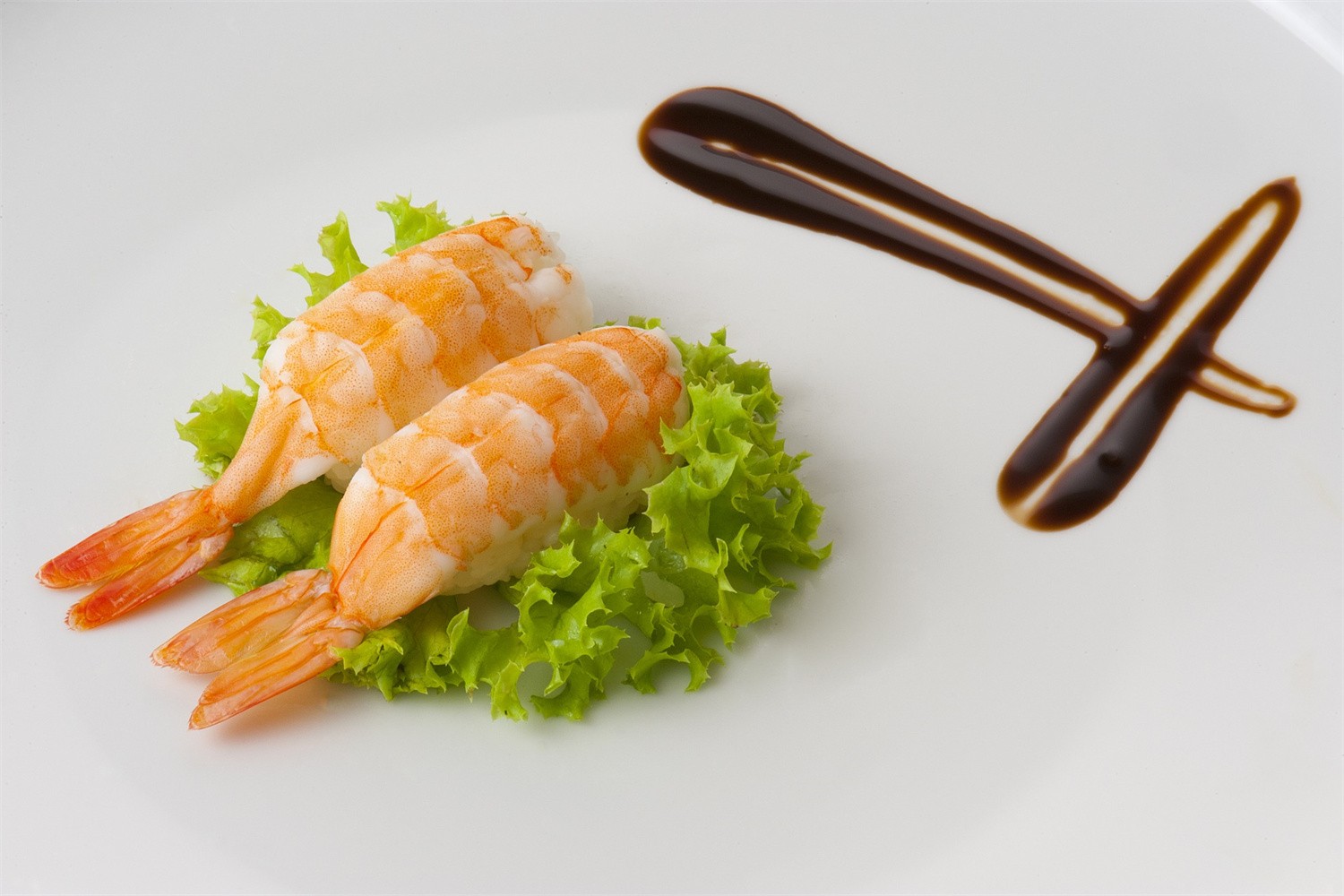 Two pieces of shrimp nigiri sushi on crisp lettuce at Osake，a Japanese Restaurant in Covington