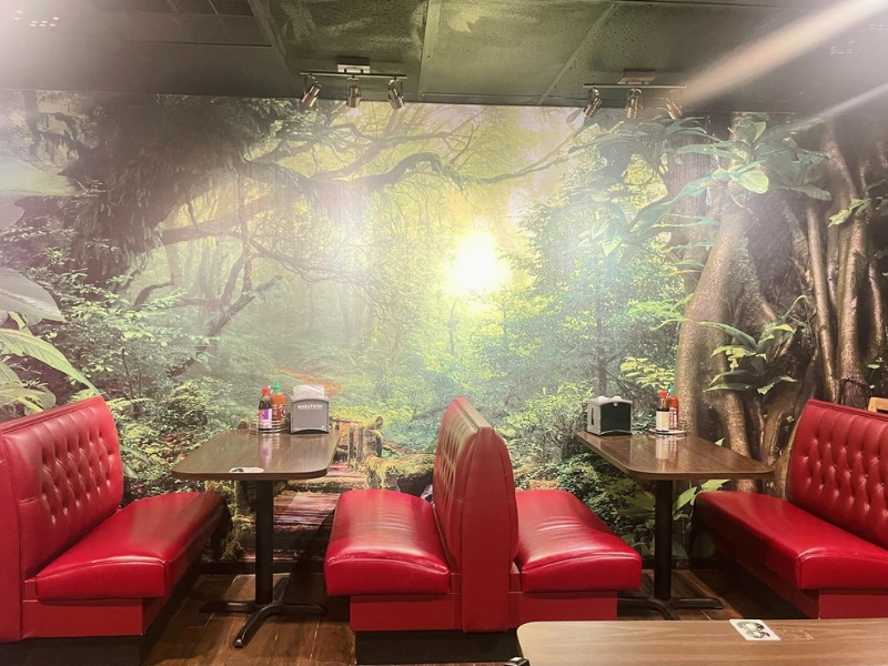 Dining area with red booths and vivid jungle mural at Pho Lover, a Vietnamese Restaurant in Galesburg