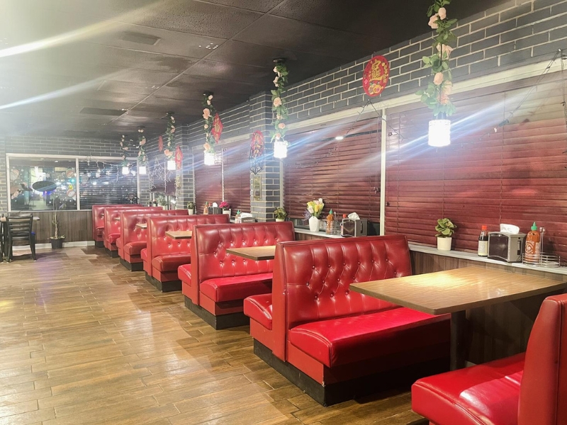 Spacious dining area with red booths, brick walls, and hanging decor at Pho Lover, a Vietnamese Restaurant in Galesburg