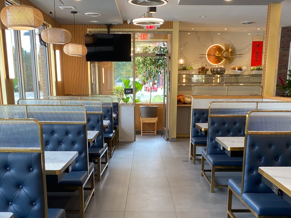 Elegant dining area with blue booths, marble tables, warm lighting at Pho Wayne, a Vietnamese Restaurant in Berwyn