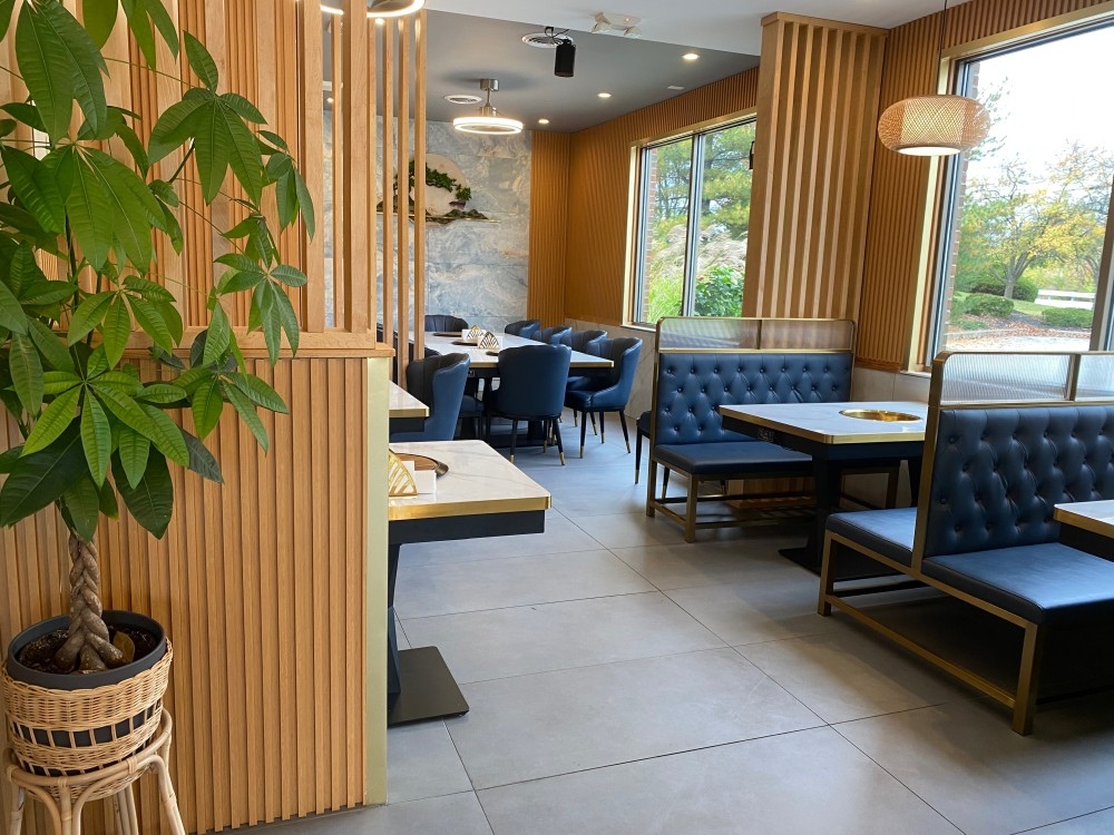 Dining area with hot pot booths, large windows, green plants at Pho Wayne, a Vietnamese Restaurant in Berwyn