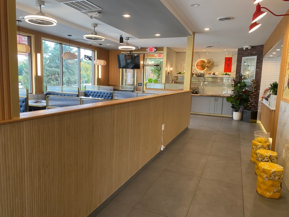 Spacious dining area with wooden partitions, plants, modern lighting at Pho Wayne, a Vietnamese Restaurant in Berwyn