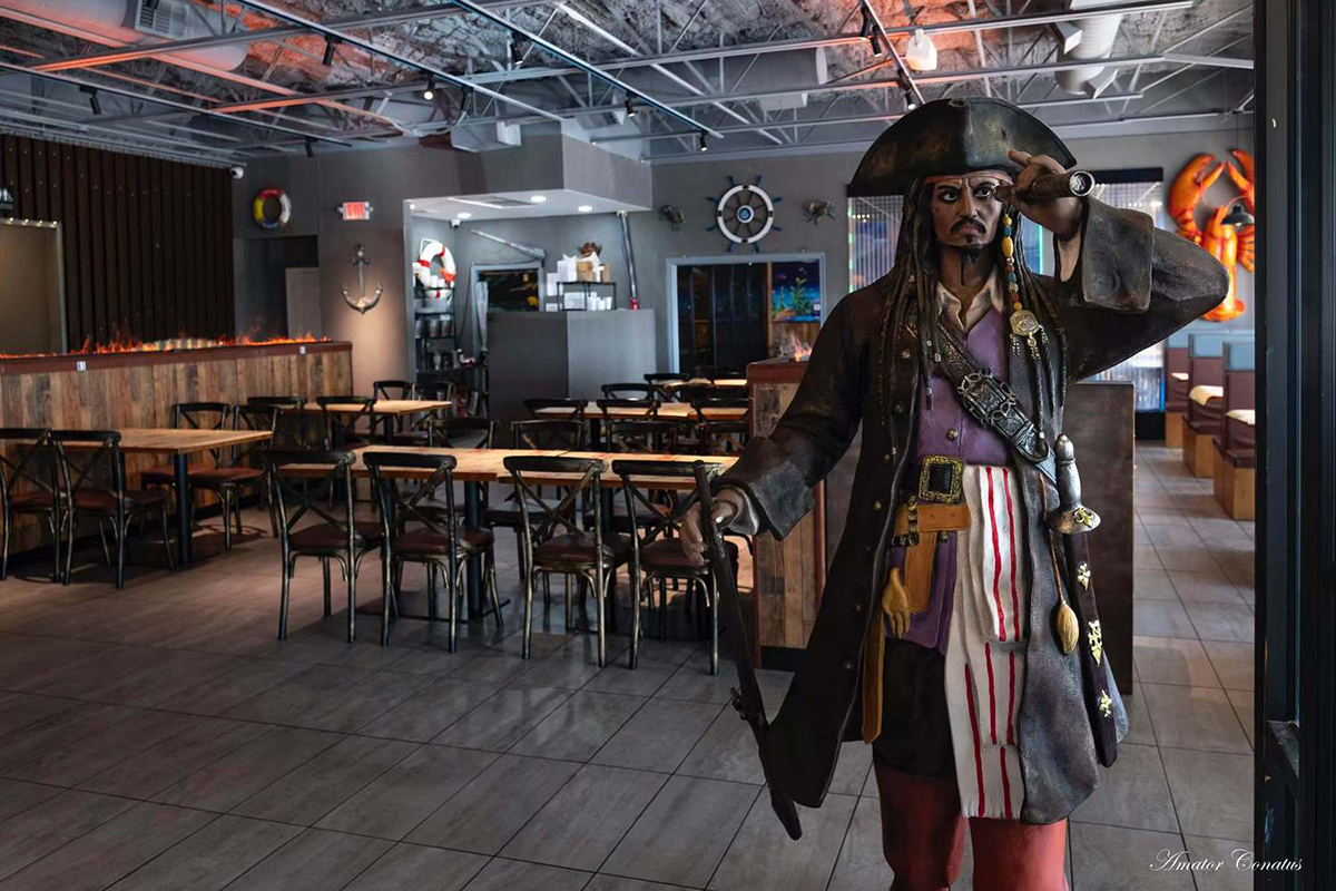A person in pirate attire stands, with the interior of the restaurant in the background of Seafood Restaurant Pier 18 Cajun Seafood & Grill with traditional decor in Texas