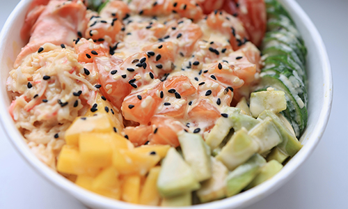 Salmon poke bowl with mango, avocado, and creamy sauce at Poke House Huntington, a Hawaiian restaurant in Huntington