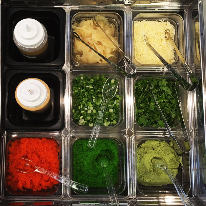 Open kitchen and order counter with menu boards, refrigerated display, and prep area at Poke Makana, a Hawaiian restaurant in Sherwood