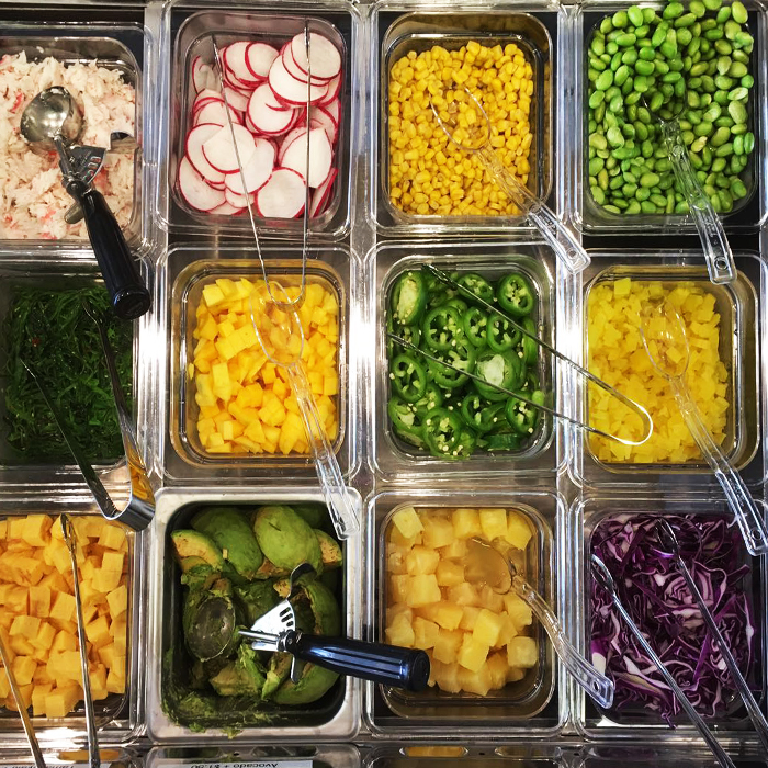 Poke bar toppings and condiments including pickled ginger, green onions, tobiko, and wasabi at Poke Makana, a Hawaiian restaurant in Sherwood