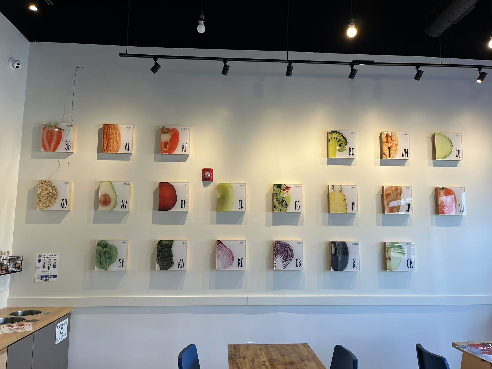 Poke-One-Poke-Bowl-Restaurant-Morris-Plains Wall display of framed vegetable slices with labels in a modern dining space.