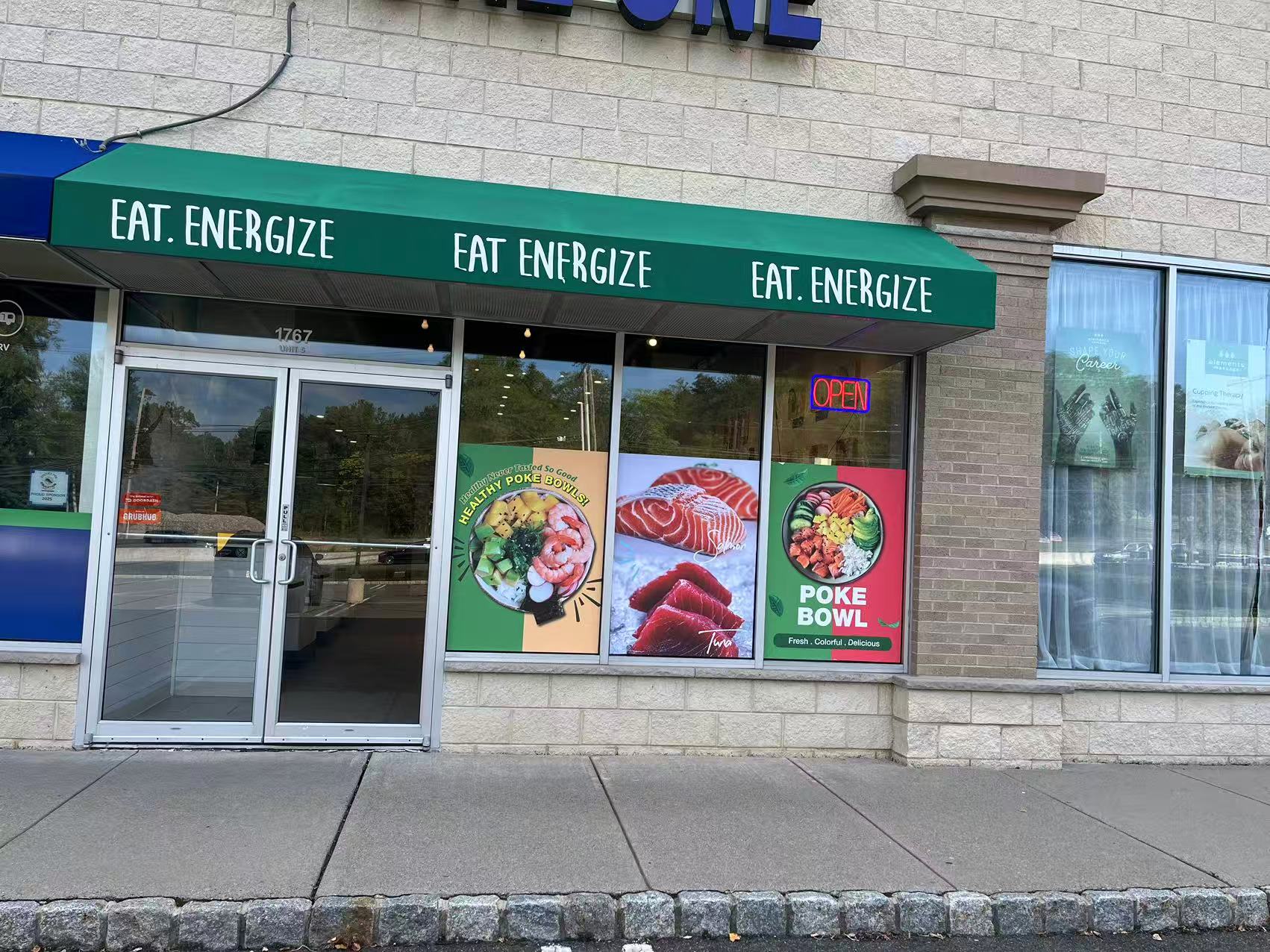 Poke-One-Poke-Bowl-Restaurant-Morris-Plains Exterior of a poke bowl restaurant with green awning and menu posters.