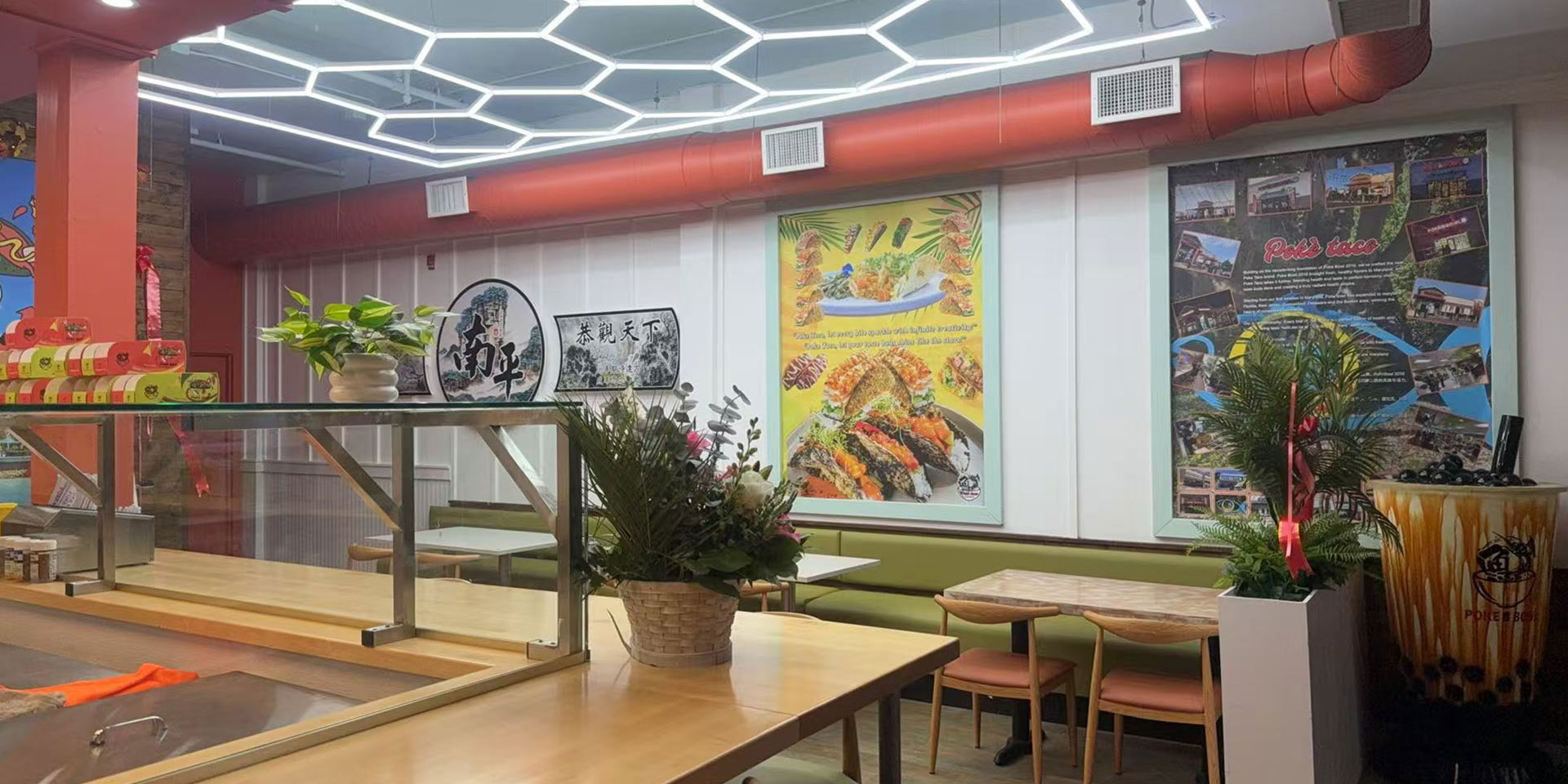Interior of a casual dining restaurant with red pipes, hexagonal lights, and "Poke Taco" posters.