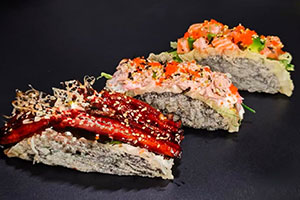 Three assorted sushi tacos with eel, spicy tuna, and salmon toppings on black background