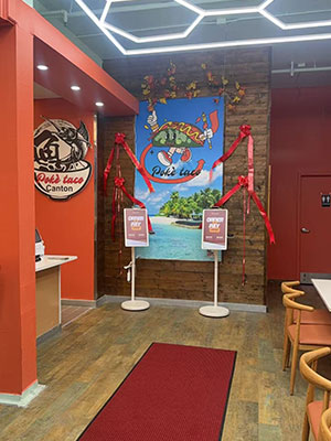 Poke Taco Canton restaurant entrance with branded wall art and red ribbon decor.