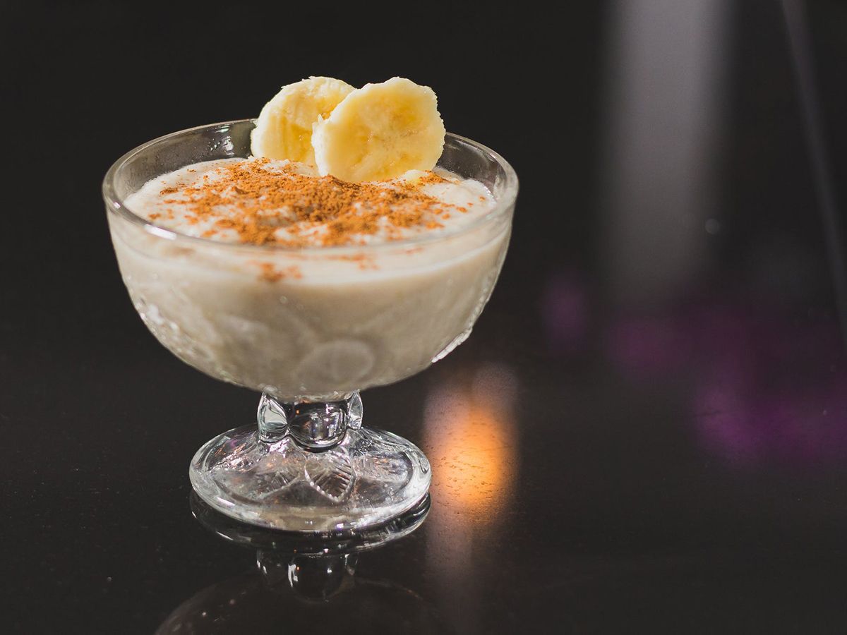 Creamy banana pudding topped with cinnamon and banana slices in a glass dish at Pop Onigiri, a Dessert Shop in Bonita Springs