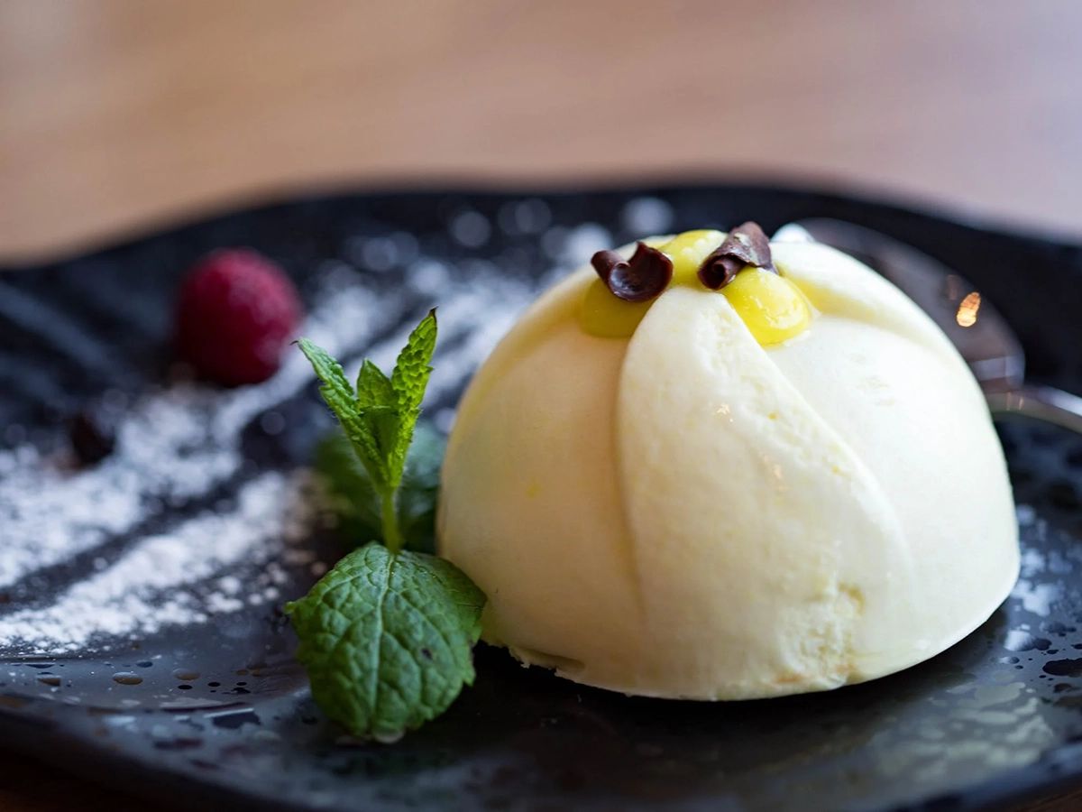 White dome-shaped dessert with mint, raspberry, and chocolate garnish at Pop Onigiri, a Dessert Shop in Bonita Springs