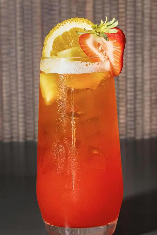 Bright orange-red iced fruit drink garnished with lemon and strawberry slices at Pop Ice Cream, a Dessert Shop restaurant in Bonita Springs