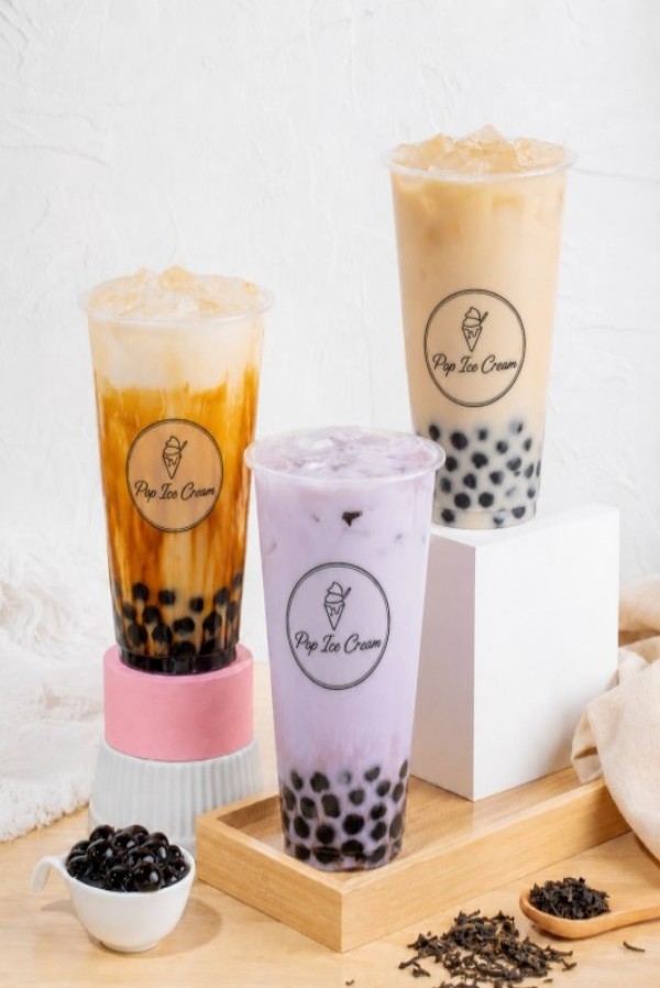 Three bubble tea drinks with tapioca pearls on wooden table