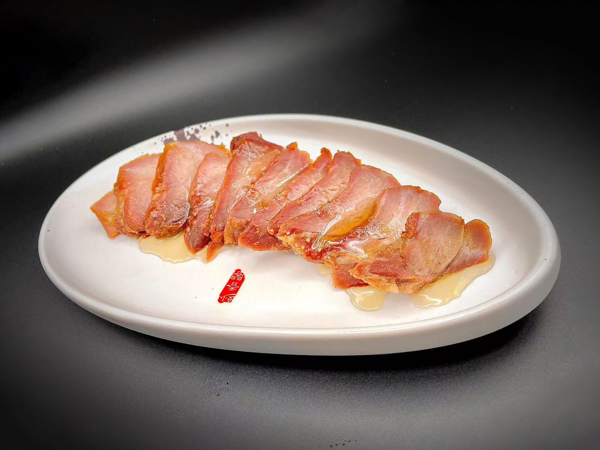 Tender sliced barbecued pork with a light glaze on a white plate at Precious, a Chinese Restaurant in Austin