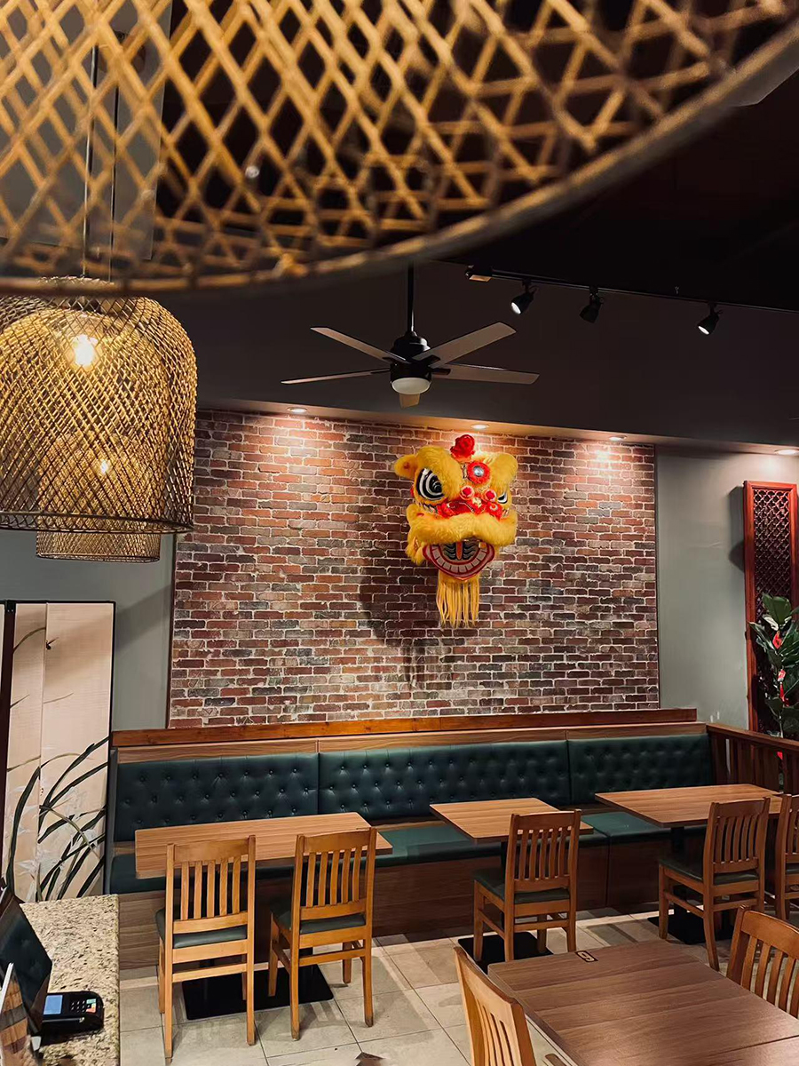 Restaurant dining area with brick wall and lion dance decor at Precious, a Chinese Restaurant in Austin