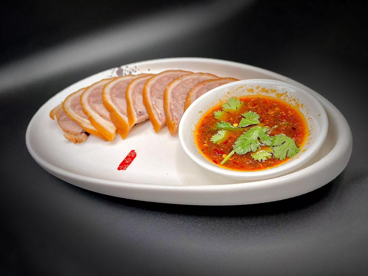 Sliced roasted duck with spicy cilantro dipping sauce on a white plate at Precious, a Chinese Restaurant in Austin