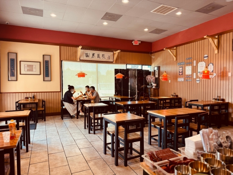 Qilu-Beef-Soup-Chinese-Restaurant-Dining-Area-Sunny-Houston Sunlit dining area with diners at Qilu Beef Soup, a Chinese Restaurant in Houston.