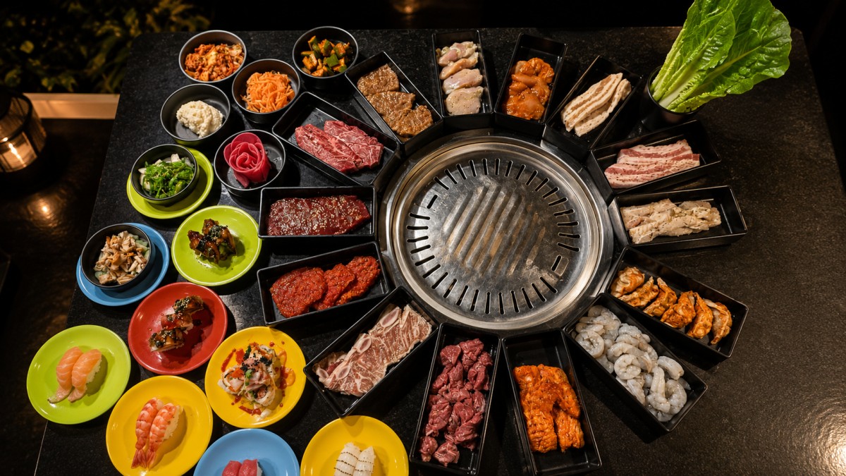 Full korean bbq platter assorted beef pork shrimp side dishes around metal grill at Q Korean BBQ & Revolving Sushi Restaurant in Huntsville