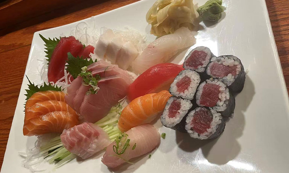 Assorted sashimi platter with tuna, salmon, white fish and tuna maki roll on glossy white square plate at Quan Izumi , an Japanese Restaurant in Centereach