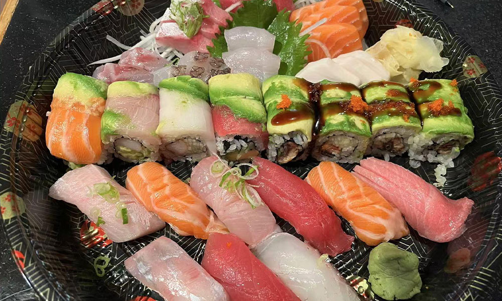 Combo platter with avocado-topped specialty rolls and assorted nigiri sushi in patterned black tray at Quan Izumi , an Japanese Restaurant in Centereach