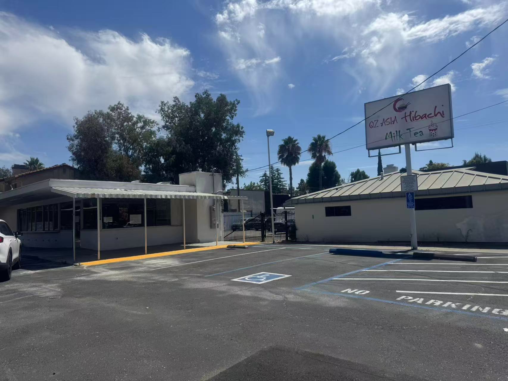 QZ-Asian-Hibachi-and-Milk-Tea-Asian-Restaurant-Carmichael Exterior of QZ Asia Hibachi Milk Tea restaurant with a parking lot and sign under a clear blue sky.