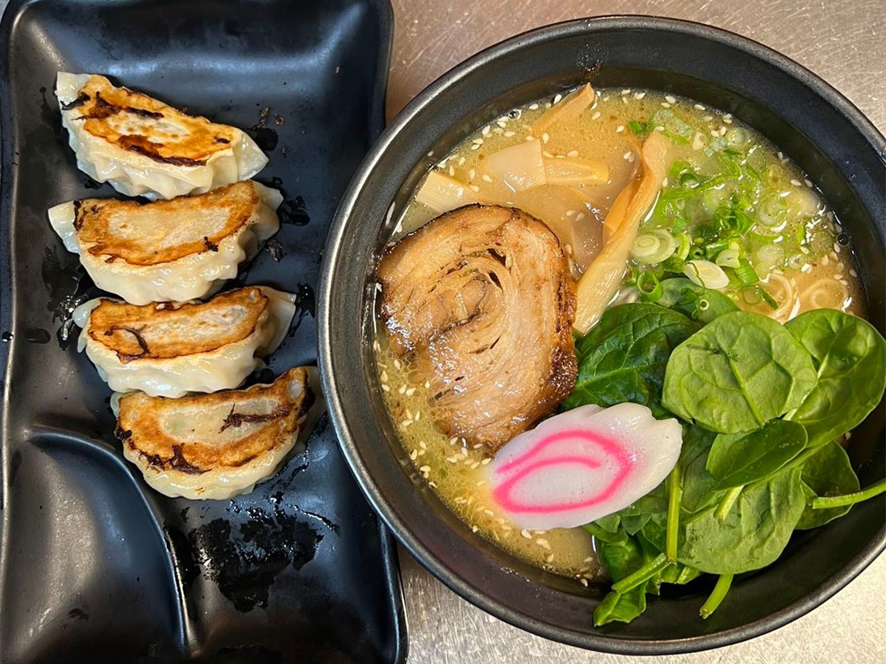Pan fried gyoza dumplings beside a bowl of tonkotsu ramen with chashu and spinach