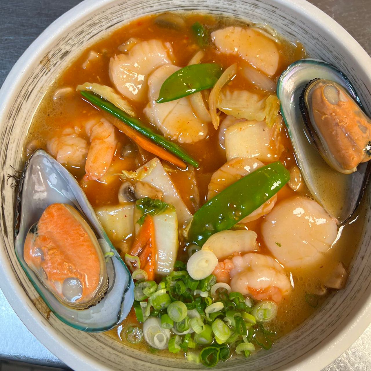 Spicy seafood soup with mussels, shrimp, scallops, snow peas and fresh green onion