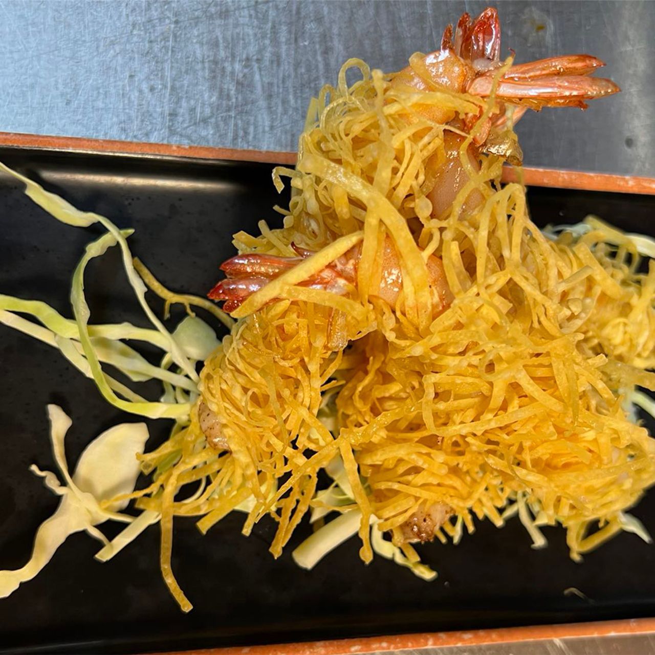 Deep fried shrimp wrapped in crispy shredded potato served on plate with cabbage