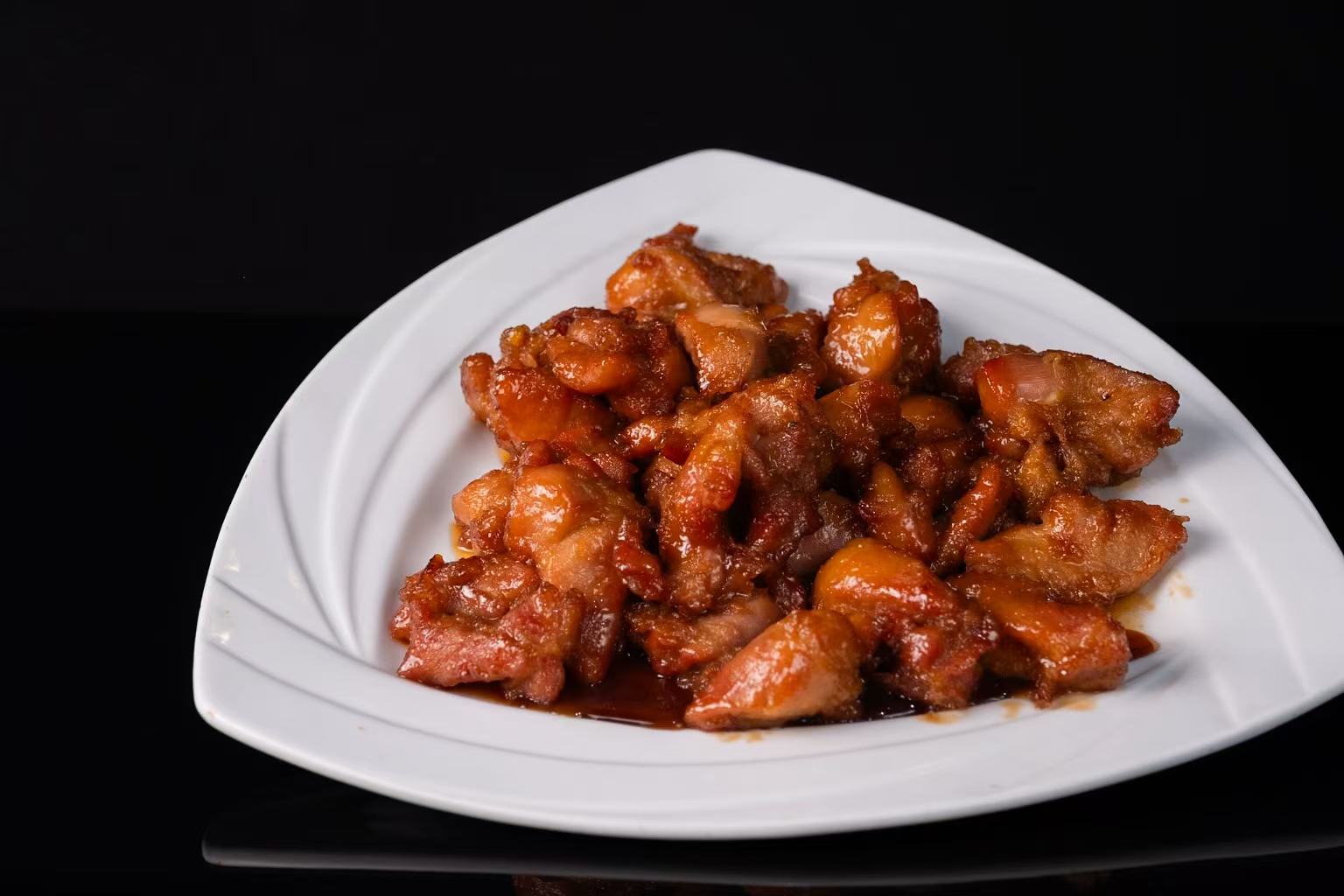 Glazed honey chicken pieces on a white triangular plate at Red Apple Buffet, a Buffet restaurant in Chicago