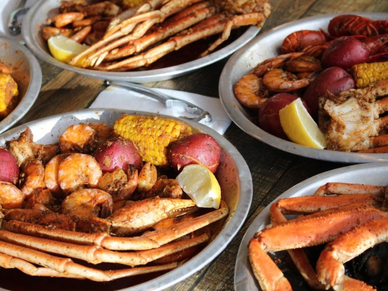 Multiple seafood boil platters with crab legs, shrimp, corn and potatoes at Red Crab, an Seafood Restaurant in Melbourne