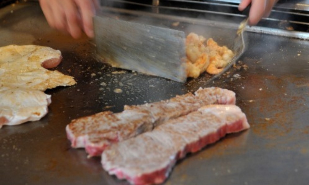 Chef cooking steak and seafood on a teppanyaki grill at Red Door Asian Bistro & Hibachi, an Asian Restaurant in Fort Lauderdale