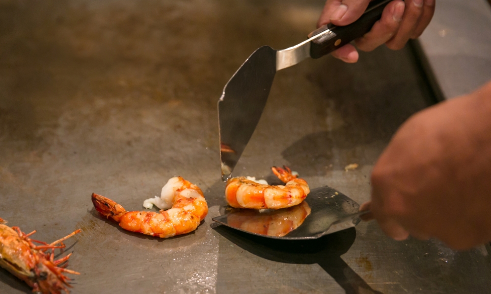 Chef grilling shrimp on a teppanyaki grill at Red Door Asian Bistro & Hibachi, an Asian Restaurant in Fort Lauderdale