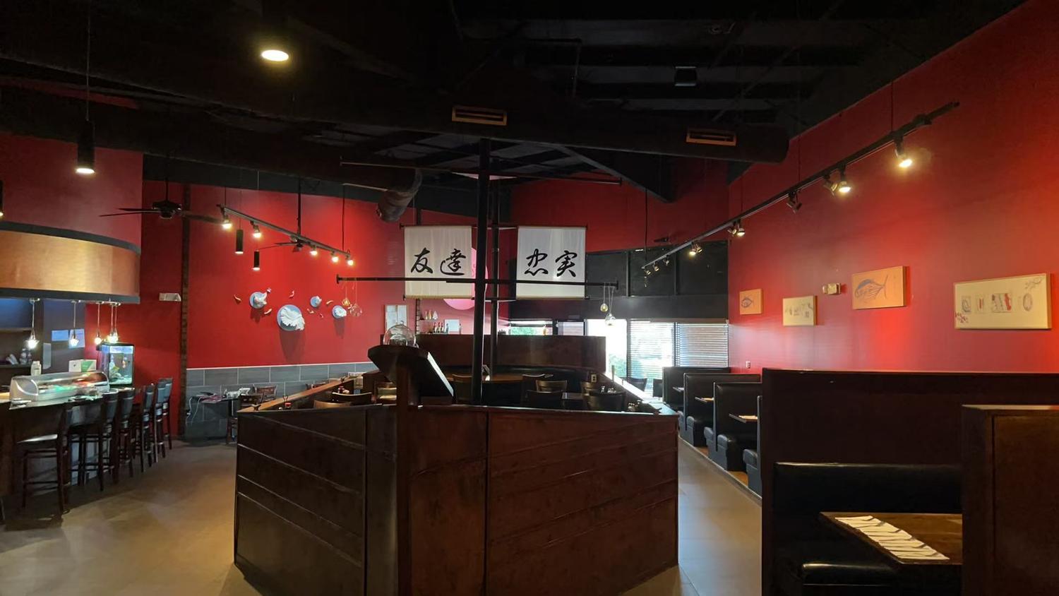 Cozy dining area with red walls, wooden booths, and Japanese calligraphy banners.