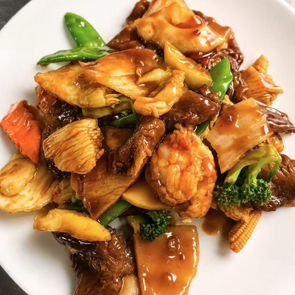 Stir-fry with meat, shrimp, broccoli, and vegetables in a brown sauce on a white plate Stir-fry with meat, shrimp, broccoli, and vegetables in a brown sauce on a white plate