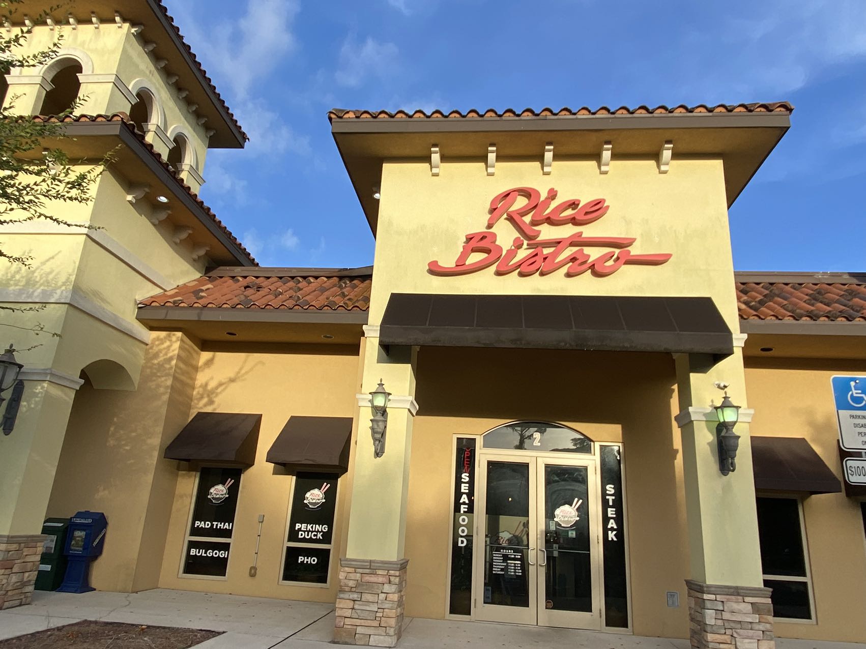 Exterior of Rice Bistro restaurant featuring signs for Pad Thai, Bulgogi, Peking Duck, and Pho.