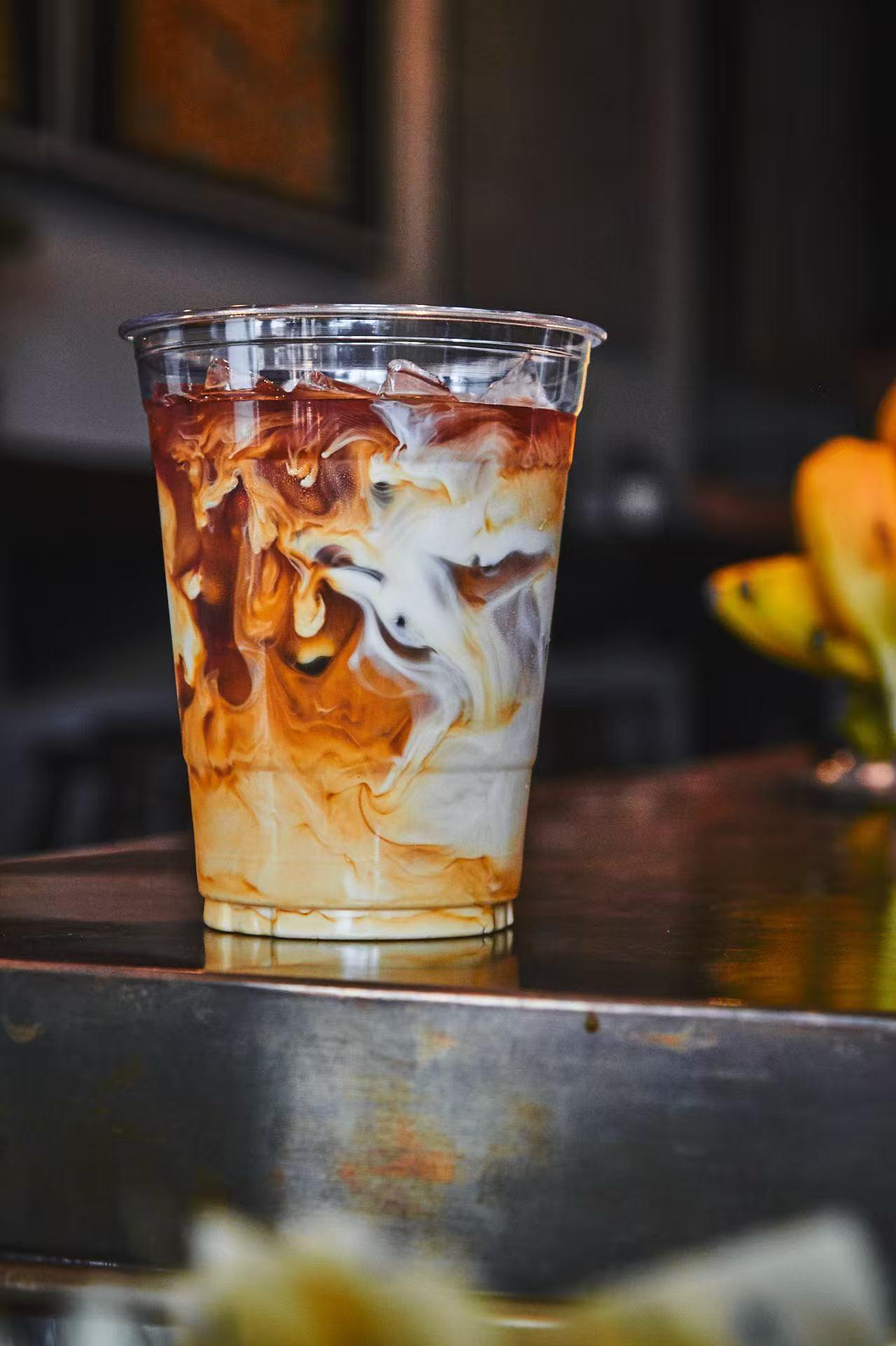 Iced latte with swirling cream and coffee at Rise & Grind Cafe, a Coffee Shop in Los Angeles