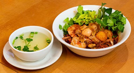 Seafood dry noodle bowl with shrimp, quail egg and fresh herbs paired with side herb broth at Saigon #1, a Vietnamese restaurant in Virginia Beach