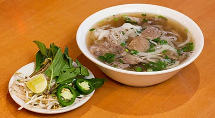 Beef pho noodle soup bowl with raw beef slices, plate of basil, jalapeño and bean sprouts at Saigon #1, a Vietnamese restaurant in Virginia Beach