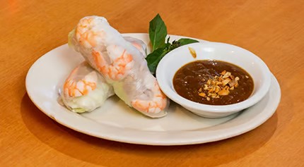 Two fresh spring rolls with translucent shrimp wrappers served with peanut dipping sauce on white ceramic plate at Saigon #1, a Vietnamese restaurant in Virginia Beach
