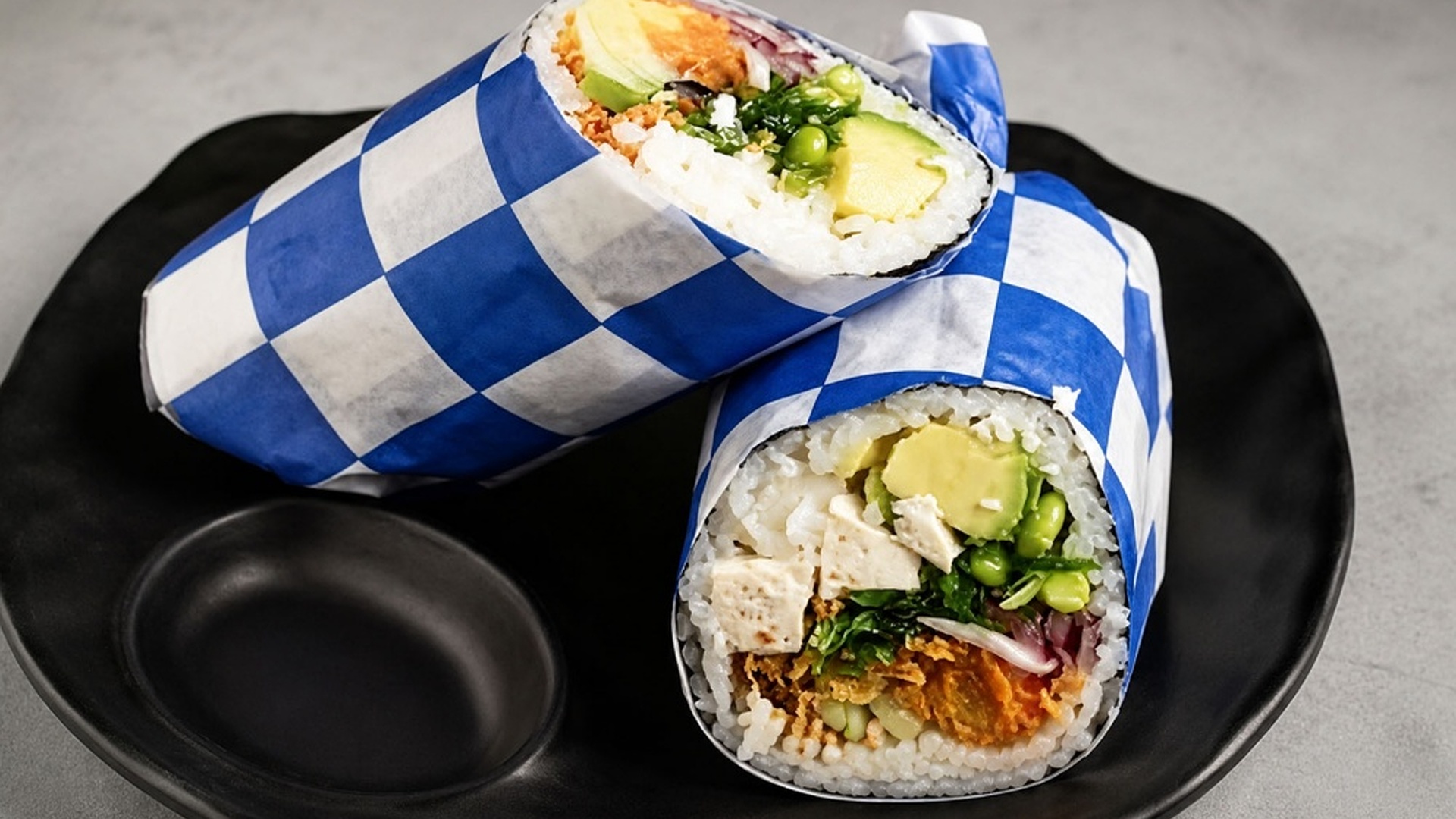 Tofu veggie sushi burrito wrapped in checkered paper at Sakana Western, a Hawaiian Restaurant in Chicago