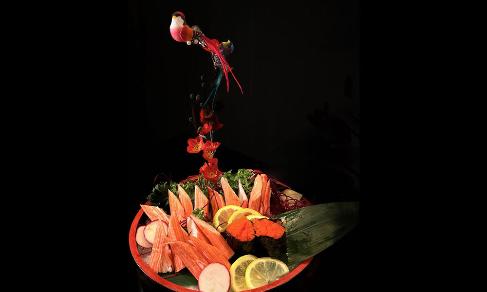 Artistic crab stick sashimi platter with citrus garnish and decorative bird ornament at Saki, a Sushi Restaurant in Clear Water