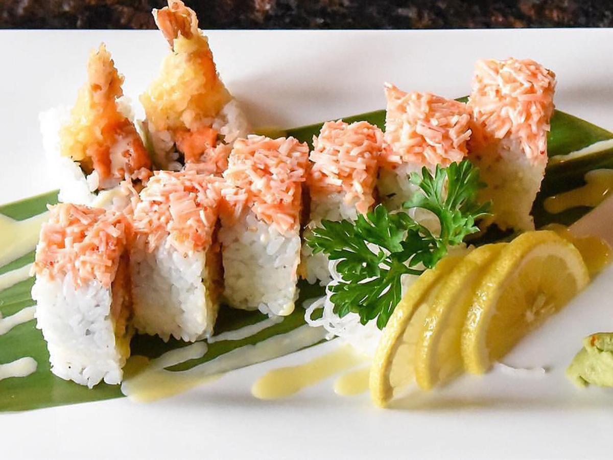 Angry Dragon Roll, served on a white plate, with tempura shrimp and other ingredients, accompanied by lemon slices, wasabi, and pickled ginger at Sakura Home，a Japanese Restaurant in Rochester